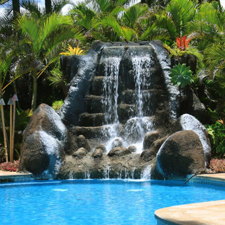 Parete con rocce artificiali a bordo piscina Rocce artificiali decorative accanto a una piscina