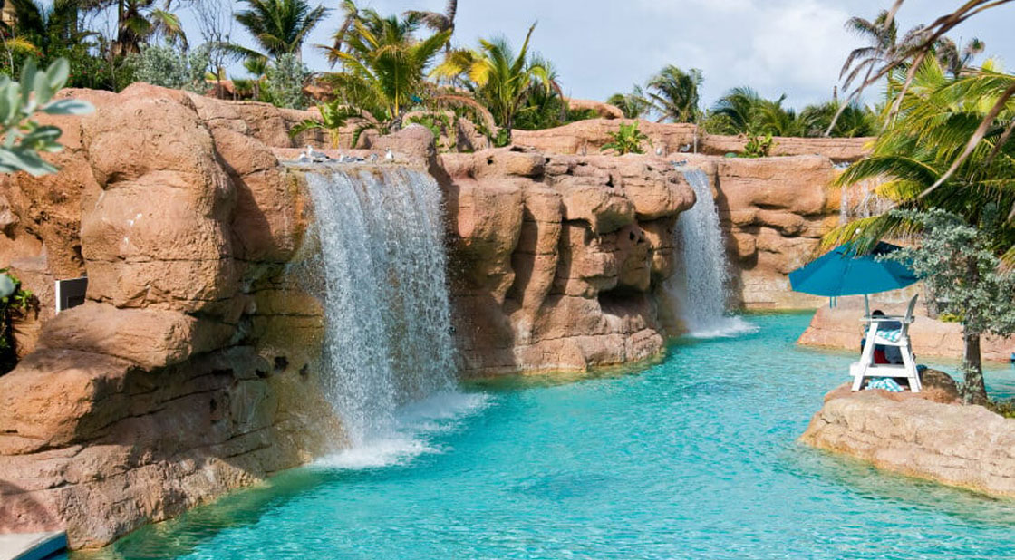 Cascate scenografiche con rocce artificiali in una laguna di un acquapark Laguna artificiale con cascate e rocce scenografiche in un parco acquatico