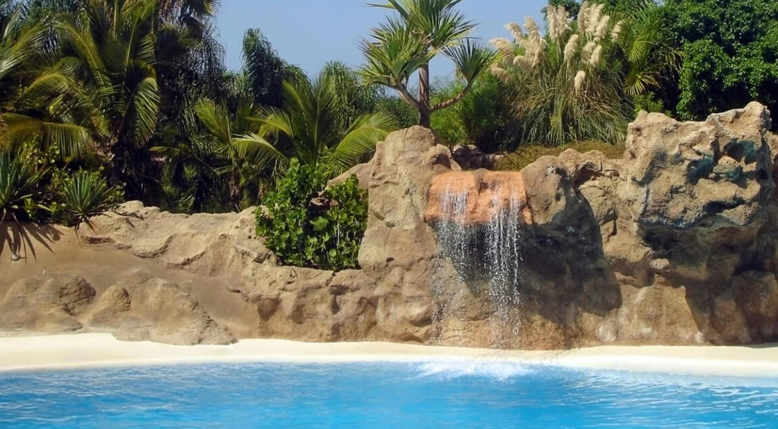 Scenografia con roccia artificiale e cascata in un parco acquatico Piscina con roccia artificiale scenografica e cascata integrata